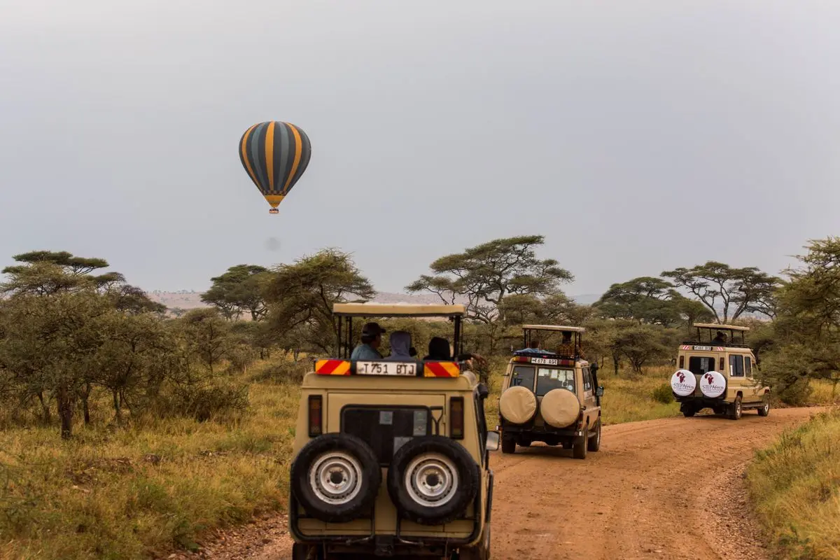 Safari vehicles and a hot-air balloon over the grasslands of Tanzania